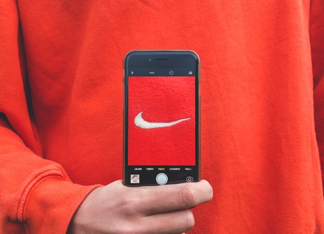 person holding iPhone taking picture on Nike label branding